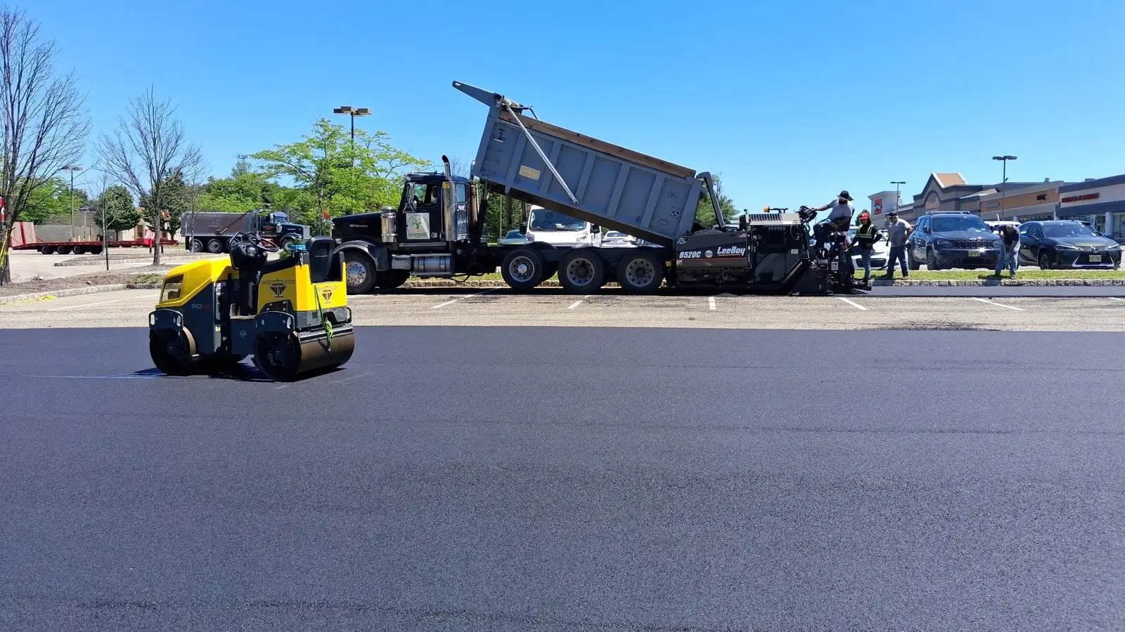 Black Diamond Paving crew laying fresh asphalt with a paver and roller on a New Jersey parking lot